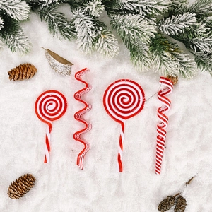 Christmas red and white candy ornaments set on snow with pine branches and cones