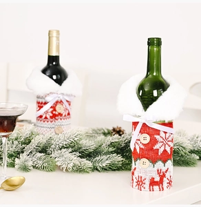Detail of knitted Christmas wine bottle cover with reindeer and snowflake patterns