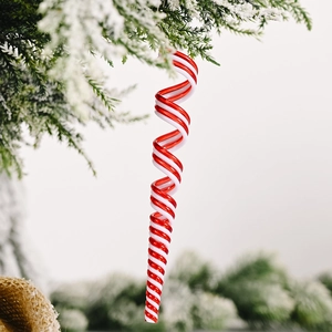 Décoration de bonbon spirale rouge et blanc suspendue sur une branche de sapin enneigée