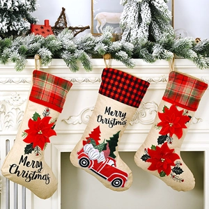 Three burlap Christmas stockings with floral and truck patterns hanging on a fireplace