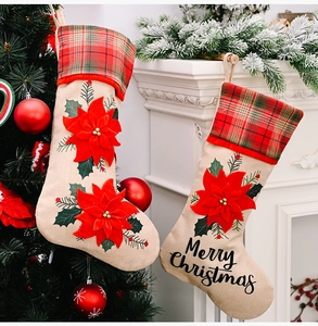 Linen Christmas stockings with red poinsettia and Merry Christmas text on a tree