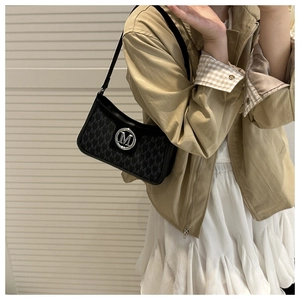Close-up of the M-letter logo and jacquard monogram texture on a black shoulder bag