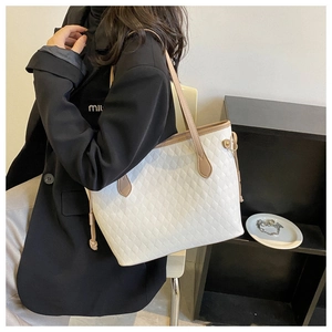 Detailed view of white quilted tote bag with contrasting beige trim on a model