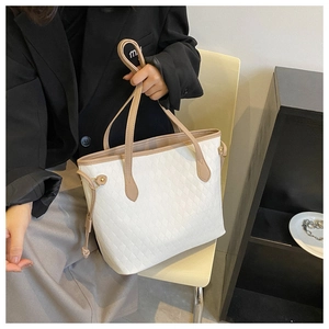 Detail of a large white quilted tote bag with beige leather handles on a chair