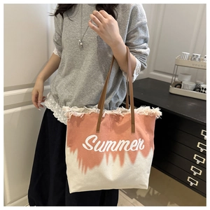 Détail du cabas en toile avec dégradé orange, bords effilochés et broderie Summer