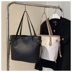 Detail of quilted tote bags in black and beige with drawstring accents and thin handles