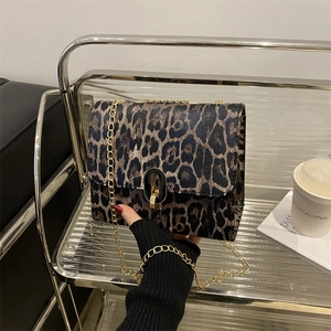 Fashionable leopard print crossbody bag with gold chain strap on a glass table