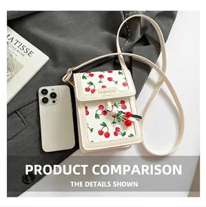 Detail of cream mini crossbody bag with red cherry prints and decorative cherry charm