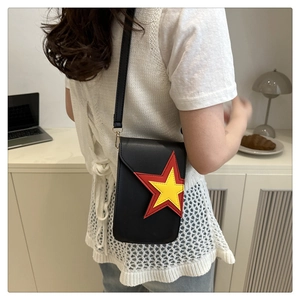 Close-up of black crossbody phone bag with red and yellow star patches on a model