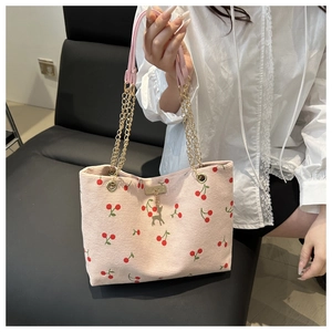 Dettaglio della borsa tote in velluto rosa con stampa ciliegia e ciondolo a cervo