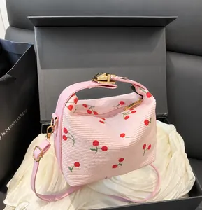Detail of pink corduroy shell bag featuring red cherry prints and golden metal hardware