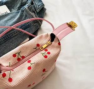 Detail of pink corduroy shell bag with cherry embroidery and smooth golden zipper