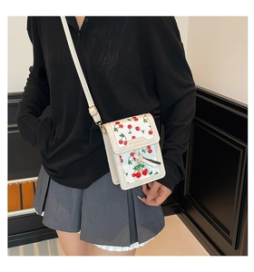 Detail of white mini crossbody bag with red cherry print and adjustable strap for women
