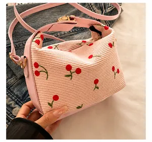 Detail of pink corduroy shell bag with red cherry embroidery and gold hardware
