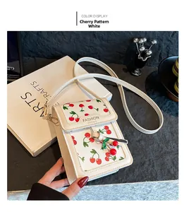 Detail of white cherry print crossbody phone bag with adjustable strap and charm