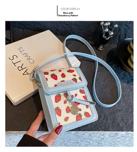 Detail of light blue PU leather bag with red strawberry print and gold tassel charm