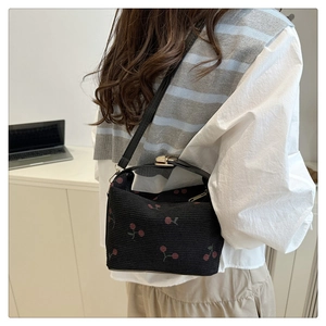 Close-up of black cherry print handbag featuring leather strap and metal twist lock