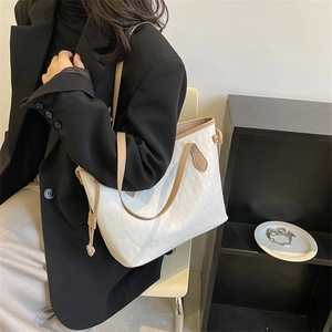 Minimalist beige quilted leather tote bag with camel straps shown on person's shoulder