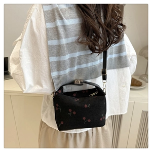 Back view of model wearing cherry print shell bag with adjustable shoulder strap