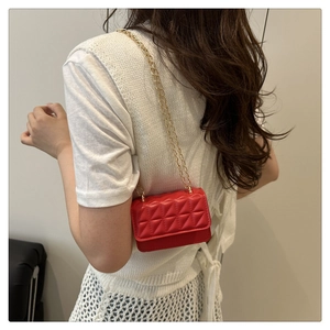 Red quilted chain crossbody bag shown on model highlighting the elegant small square design