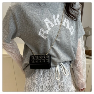 Detalle de mini bolso acolchado negro con cadena dorada usado por una modelo