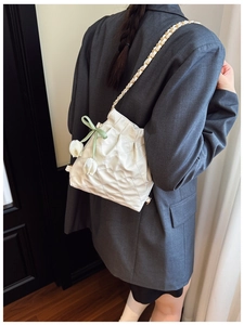 Detail view of white quilted drawstring bag with gold chain and tulip floral ornament
