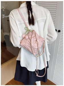 Detailed view of pink quilted shoulder bag featuring tulip charm and gold chain strap