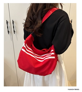 Gros plan d'un grand sac Hobo en toile rouge avec trois bandes blanches sport