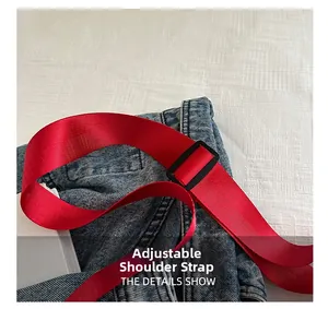 Détail de la bandoulière réglable en nylon rouge avec boucle noire sur tissu denim