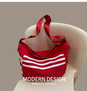 Détail du sac bandoulière en nylon rouge avec trois bandes blanches sur siège beige