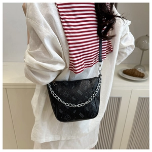 Detail of black lychee grain leather bucket bag with bear embossing and silver chain