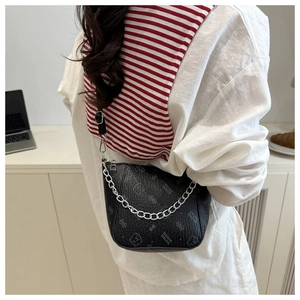 Detail of black embossed leather crossbody bucket bag with chain and logo on model