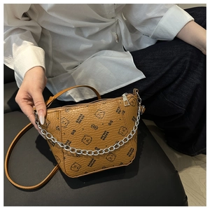Detailed view of brown bucket bag with cartoon bear print and silver chain strap