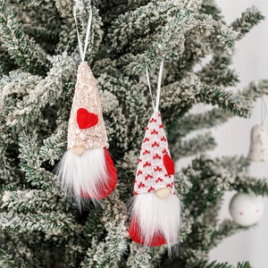 Set of two Valentine's Day gnome ornaments with red hearts hanging on a Christmas tree