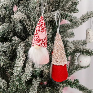 Handmade Valentine's Day gnome ornaments hanging on a snowy Christmas tree branch