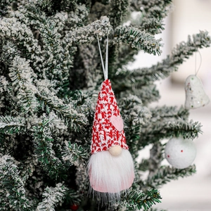 Macro shot of Valentine Gnome plush with red polka dot hat on a snowy Christmas tree