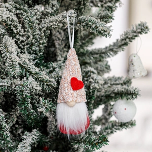 Hanging handmade Valentine gnome ornament with red heart and beige plaid hat on snowy branch