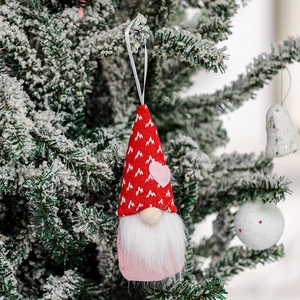 Close-up of Valentine's gnome plush hanging on a snowy tree branch with pink heart detail