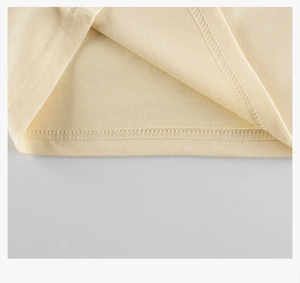 Detail of double-needle stitching on hem of beige cotton long sleeve kids t-shirt