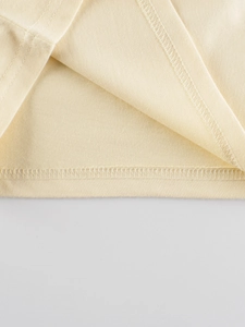 Close-up of cream cotton long sleeve t-shirt showing high-quality hem stitching details