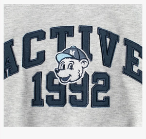 Détail de la broderie ours dessin animé 1992 sur un sweat gris en polaire