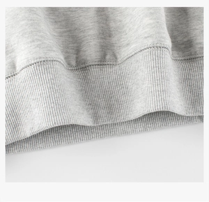 Gros plan des poignets en maille côtelée et texture polaire sur un sweat gris clair