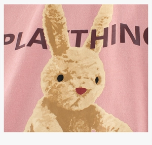 Détail du tissu en coton rose avec imprimé lapin jaune et texte PLAYTHING brodé