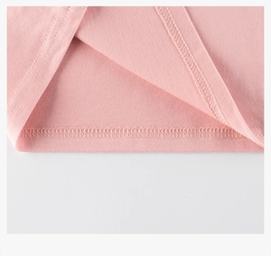 Détail du bas d'un t-shirt rose pour fille montrant les coutures plates et l'ourlet