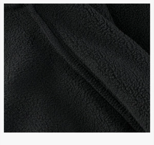 Macro shot of high-quality black polar fleece fabric with neat stitching and soft texture