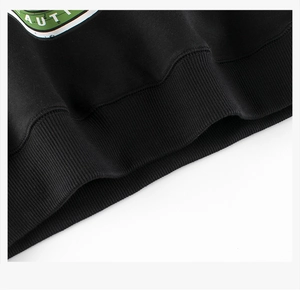 Detail of black sweatshirt ribbed hem with vintage green print and precise stitching
