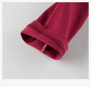Detail view of smooth stitching and hem quality on deep red long sleeve knit shirt cuff