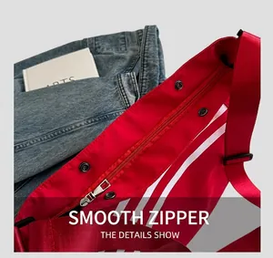 Détail de la fermeture éclair métallique et des rayures sur le sac en toile rouge