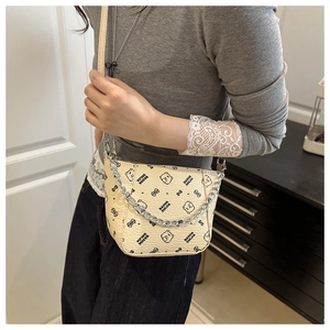 Close-up of a cream bucket bag featuring cartoon bear patterns and a metal chain strap