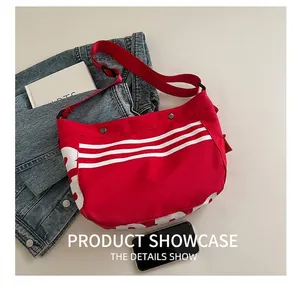 Détail du sac fourre-tout en toile rouge avec rayures blanches et bandoulière